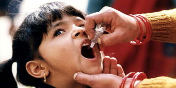 A young Indian girl receiving a dose of oral polio vaccine by a trained healthcare worker. Original image sourced from US Government department: Public Health Image Library, Centers for Disease Control and Prevention. Under US law this image is copyright free, please credit the government department whenever you can”.